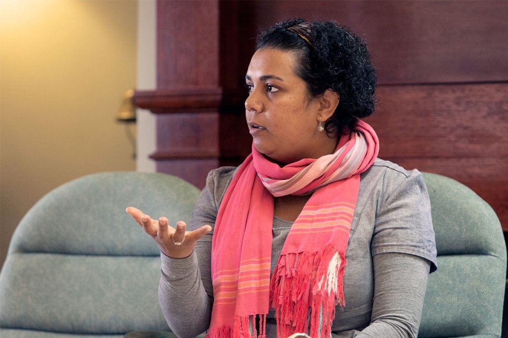 A person speaking while sitting indoors.