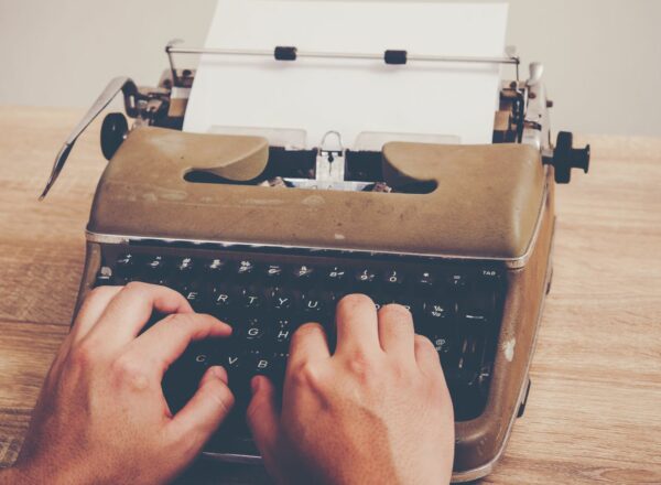 Hands typing on a typewriter.